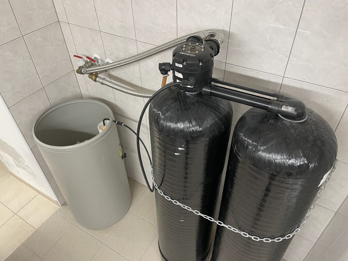 A twin-tank water softener beside its brine tank